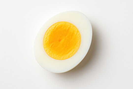 Hard boiled egg cut in half showing yolk and white on white background