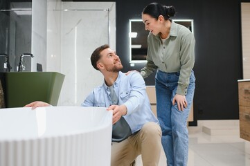Couple choosing modern bathtub in bathroom furniture store
