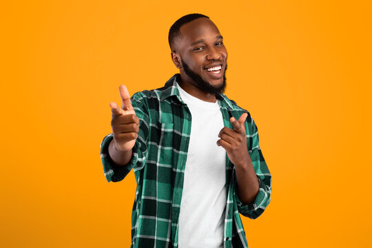 Hey You. Positive Black Bearded Guy Pointing Fingers At Camera Smiling Posing Over Yellow Background. Studio Shot. Advertisement Banner With Happy Man Gesturing You're Next