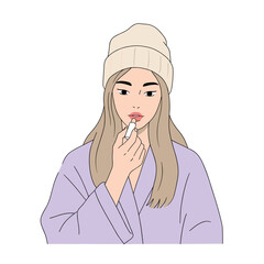 Young woman applying lip balm while wearing a hat and robe  