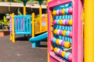 Brightly colored playground equipment features a pink abacus, slides, and climbing structures....