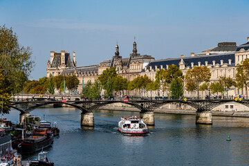 Scenic river cruise on the Seine, showcasing a tour boat, historic bridges, and the iconic Louvre Museum.