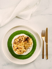 Cauliflower steak with green and white puree. Grilled cauliflower as vegan and vegetarian food concept. Healthy food ideas and menu. Copy space for text