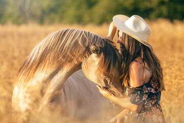 Woman bonding with horse in golden summer field