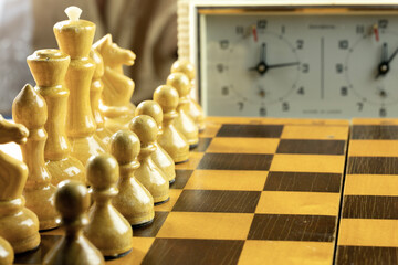 A close-up of a wooden chessboard with light and dark squares. 