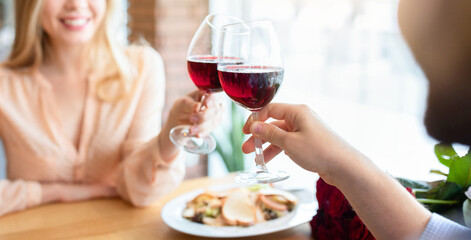 Loving millennial couple toasting red wine, saying cheers, celebrating Valentine's Day in...