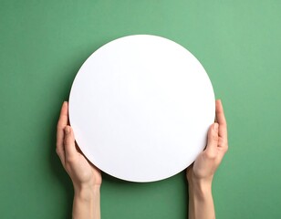 Blank white circle held by hands against green backdrop