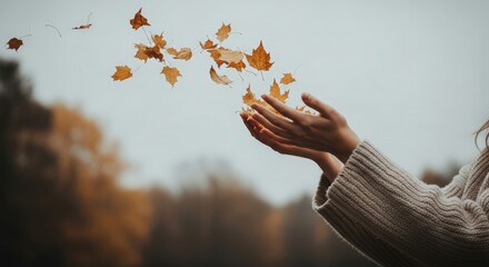 Caucasian woman with cupped hands catching falling autumn leaves. Autumn season concept for coziness, freedom, and happiness.