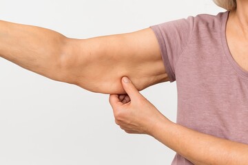 Close-up of a caucasian woman s arm with loose skin in a pink shirt. concept of aging, skincare, body awareness, health.