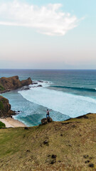 Aerial Drone view Woman stands on a hill overlooking the blue sea and sunset at Merese Hill,...