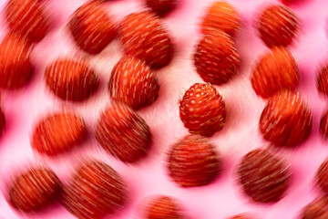 A close-up view of red lychee fruits scattered on a pink background.