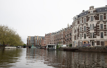 A view along a canal in Amsterdam, Holland showing the typical narrow houses lining the canal.