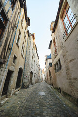 An eye-level perspective of a narrow cobblestone street lined with old stone buildings during the...
