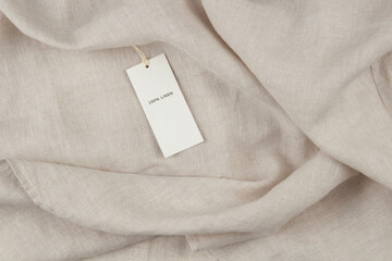 Natural linen fabric garment, bedding, or home textile with white paper label price tag. Natural sustainable materials products