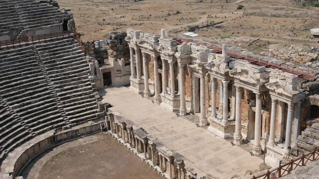 Explore the stunning ancient theatre at Pamukkale, showcasing intricate architecture and rich history, nestled among the ruins of an ancient settlement.