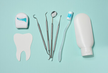 White tube of toothpaste, dental floss in white case, dental instruments and paper cut out white...