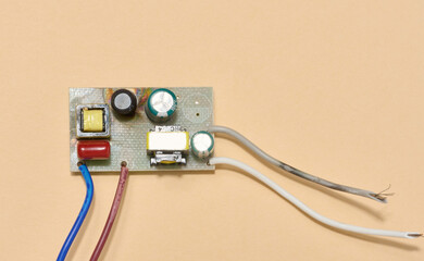 Electronic board with wires located on a beige background. Top view