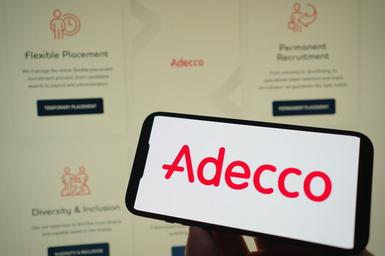 Roosendaal, The Netherlands - August 03, 2025: A mobile phone displaying the company logo of Adecco, with the company website in the background.