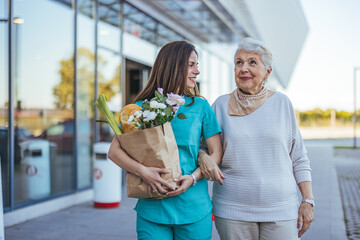 Smiling Healthcare Worker Assisting Elderly Woman With Groceries Outdoors