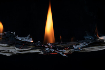 burning grey paper, glowing edge of paper on a black background