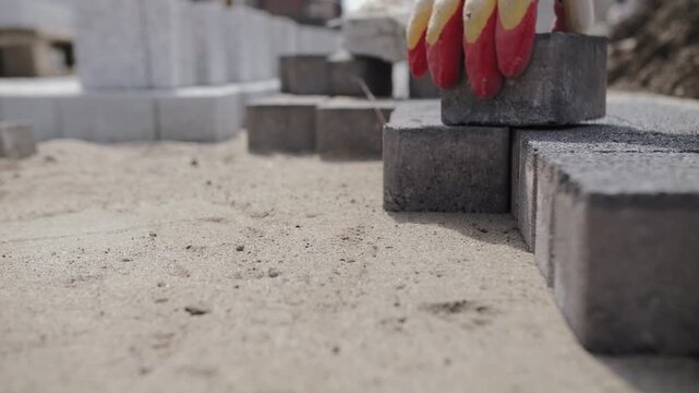 Worker laying paving stones on sand base