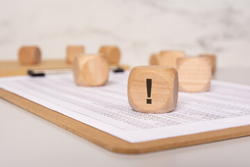 wooden cube with exclamation mark on financial chart paper, concept of warning or alert