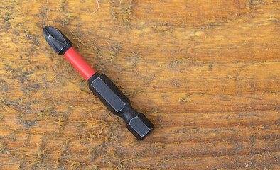 Magnetic screwdriver bit with red insulation on rustic wooden background