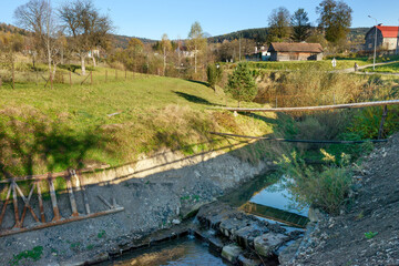 Small decrepit pedestrian bridge across narrow riverbed, Skhidnytsia, Western Ukraine.