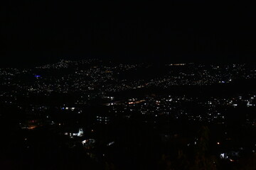 Shillong city at night, illuminated by countless lights against a dark sky, showcasing a bustling urban landscape.