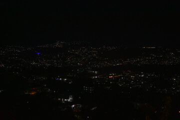 Shillong city at night, illuminated by countless lights against a dark sky, showcasing a bustling urban landscape.