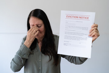 Woman crying while holding an eviction notice letter.