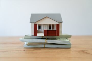 Concept of real estate value or price. Model house on top of a pile of cash.