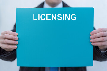 Business person holding turquoise banner with word: LICENSING. License agreement. Law template for...
