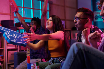 Multiethnic group of young adults cheering and celebrating while watching sports game on...