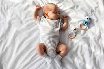 Portrait Of Adorable Newborn Child Napping On Bed With Rattle Toys Around, Cute Little Infant Baby...