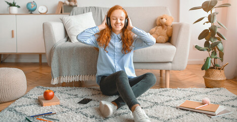 Rest Concept. Positive smiling red-haired teenage girl listening to music with closed eyes,...