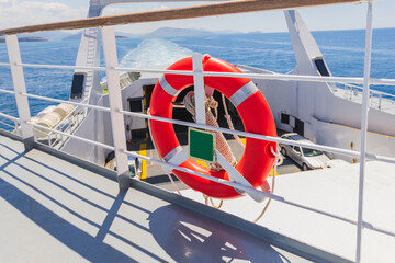 Red Life Ring Safety Equipment On White Ferry Boat Deck With Ocean View And Blue Sky Background...