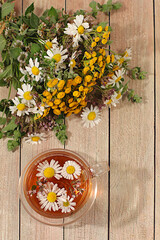 Tea from wild medicinal herbs on a wooden table, a bouquet of St. John's wort, oregano, mint,...