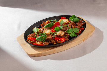 Traditional Korean stir-fry made with kimchi, red chili peppers, bell pepper and fresh herbs, served on a hot pan. Bright, spicy, authentic Asian food.
