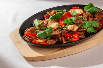Traditional Korean stir-fry made with kimchi, red chili peppers, bell pepper and fresh herbs, served on a hot pan. Bright, spicy, authentic Asian food.