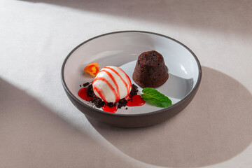 Warm chocolate fondant served with vanilla ice cream, strawberry syrup, mint leaf and edible flower...