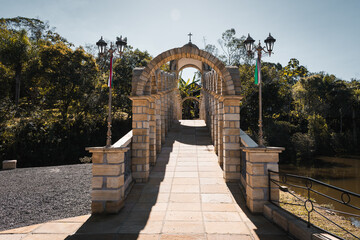 Ponte de Pedra com Arcos e Lampiões em um Jardim com Árvores