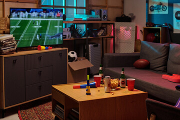 Living room scene showing group of young adult men watching football game on television, snack...