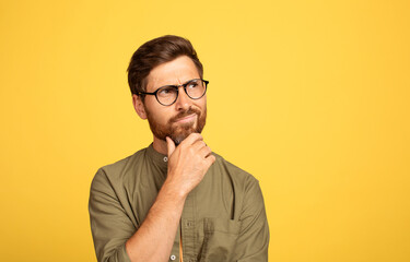 A bearded man in his 40s, wearing glasses and a casual outfit, appears to be deep in thought...