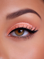 Fototapeta premium pastel peach background with glitter eyeliner closeup
