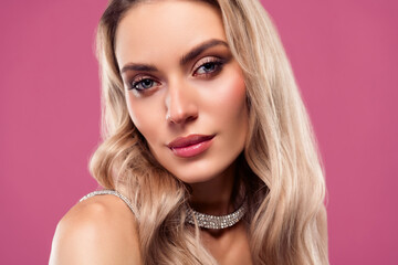 Portrait of a young elegant blonde woman with glamorous makeup wearing a sparkling necklace against...