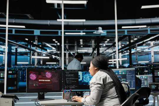 Artificial intelligence data center system administrator disturbed by virus breaching security. African american woman in AI server hub afraid by hacker attack stealing sensitive information. - Powered by Adobe