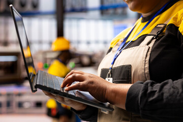 Female technician upgrading assembly line operation in smart manufacturing plant. Closeup of...