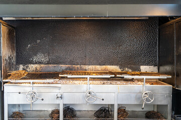 A professional charcoal grill, equipped with adjustable grates and organized tools, is ready for high-volume cooking.