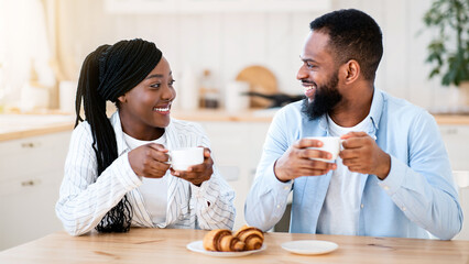 Domestic Morning. Portrait Of Young Happy Black Couple Having Coffee And Croissants For Breakfast, Cheerful African American Man And Woman Sitting At Table In Kitchen, Enjoying Time Together, Closeup
